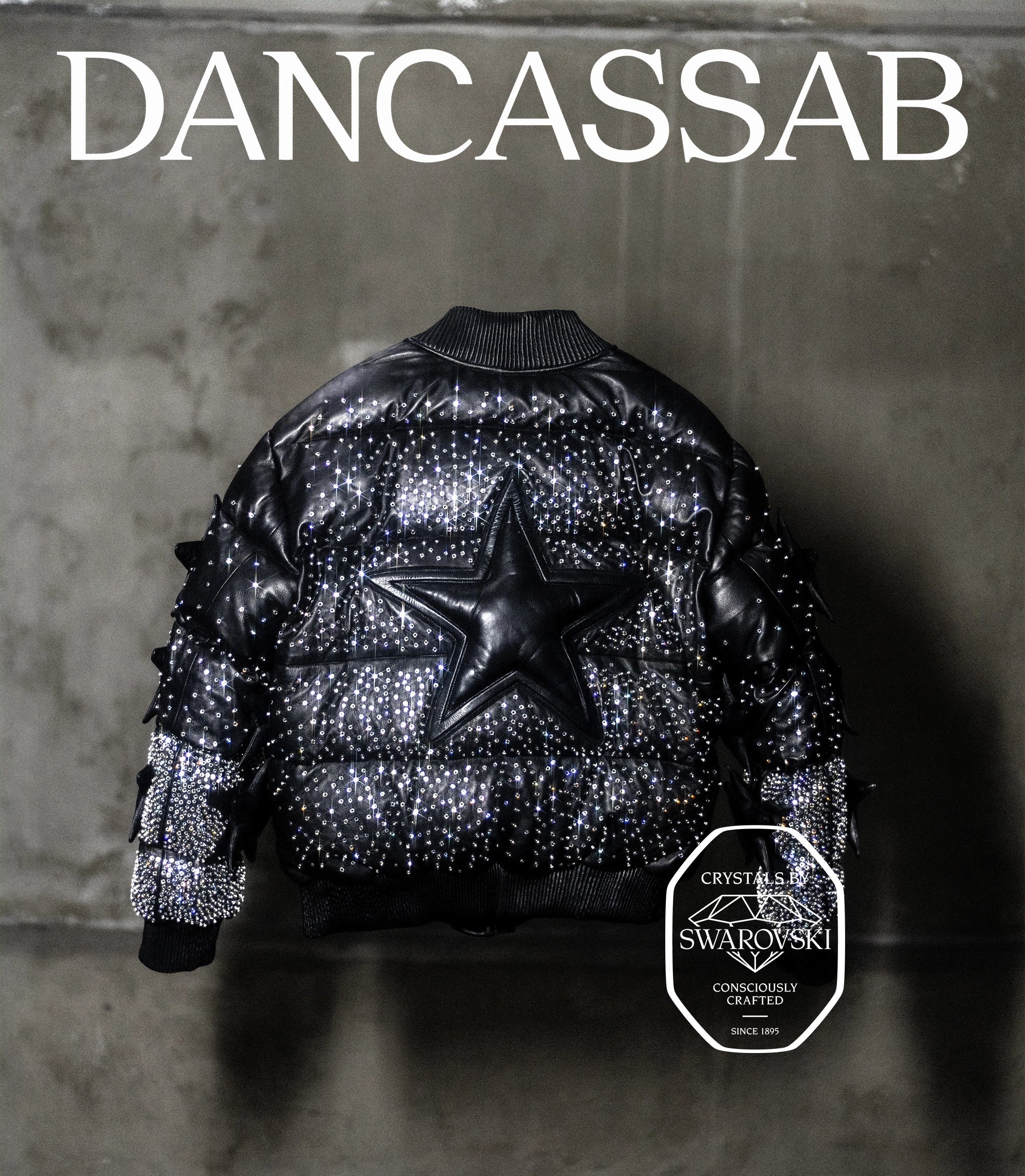 Black puffer jacket with star design and Swarovski crystals on a gray background, featuring the brand 'DANCASSAB'.